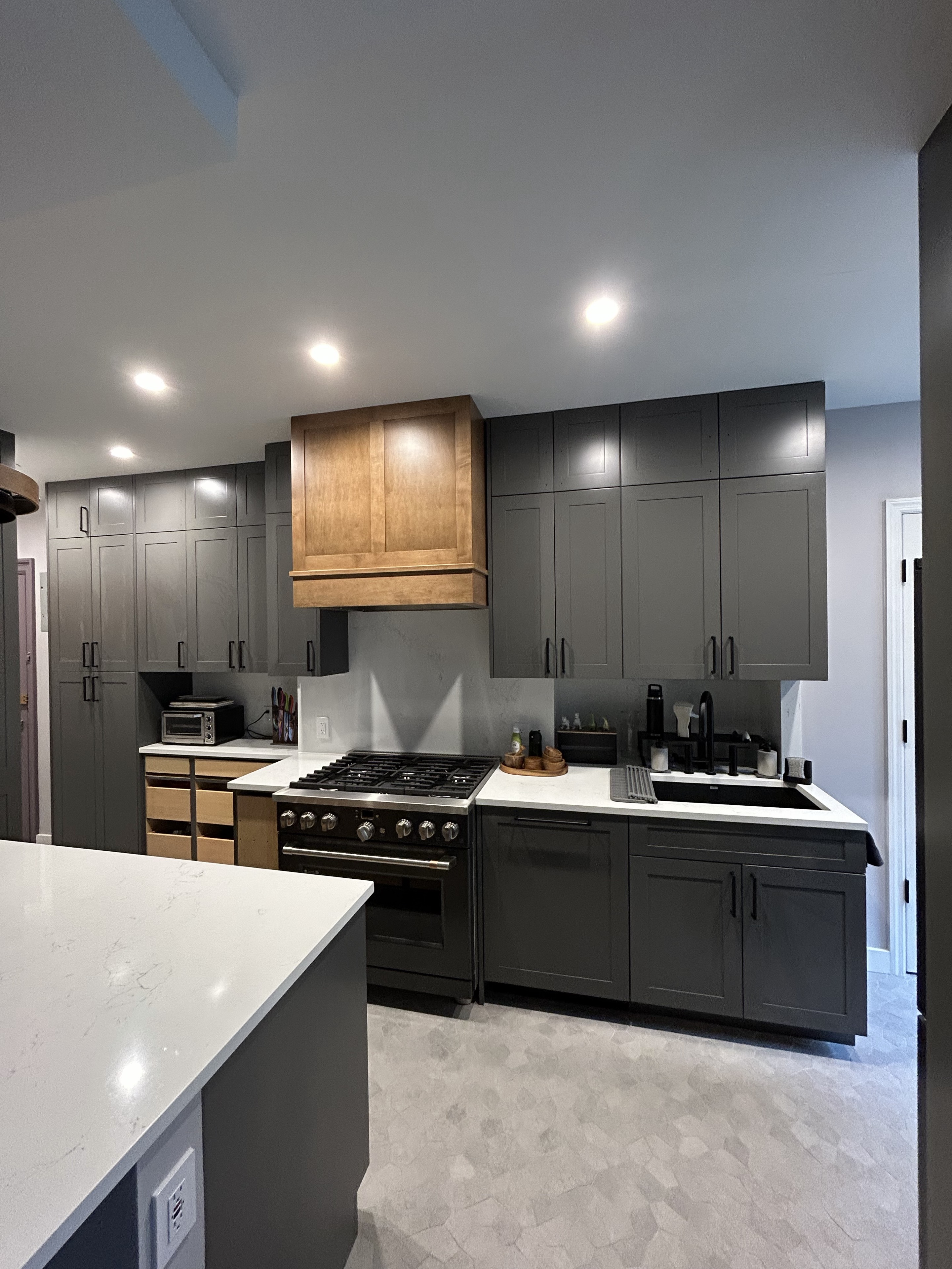 SAL kitchen project with charcoal cabinetry and a natural wood range hood